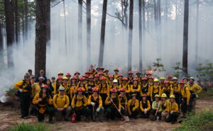 Group photo of Fire Week participants in front of a prescribed burn at North Carolina State Parks.
